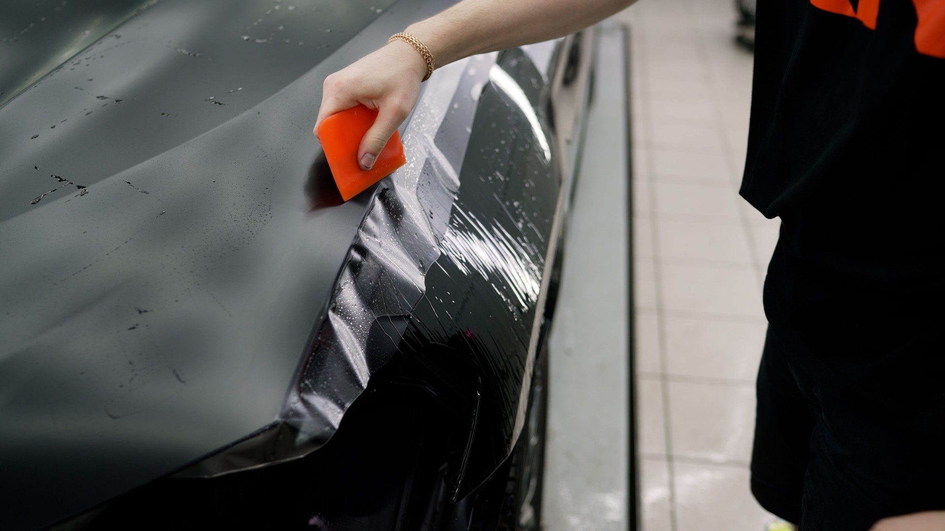 Professional applying protective film on car hood