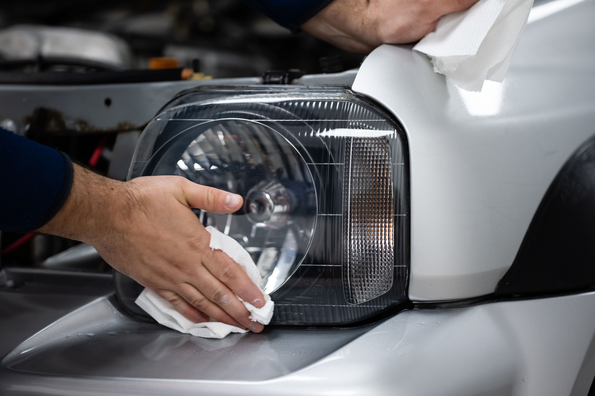 Hands cleaning car headlight during automotive detailing service